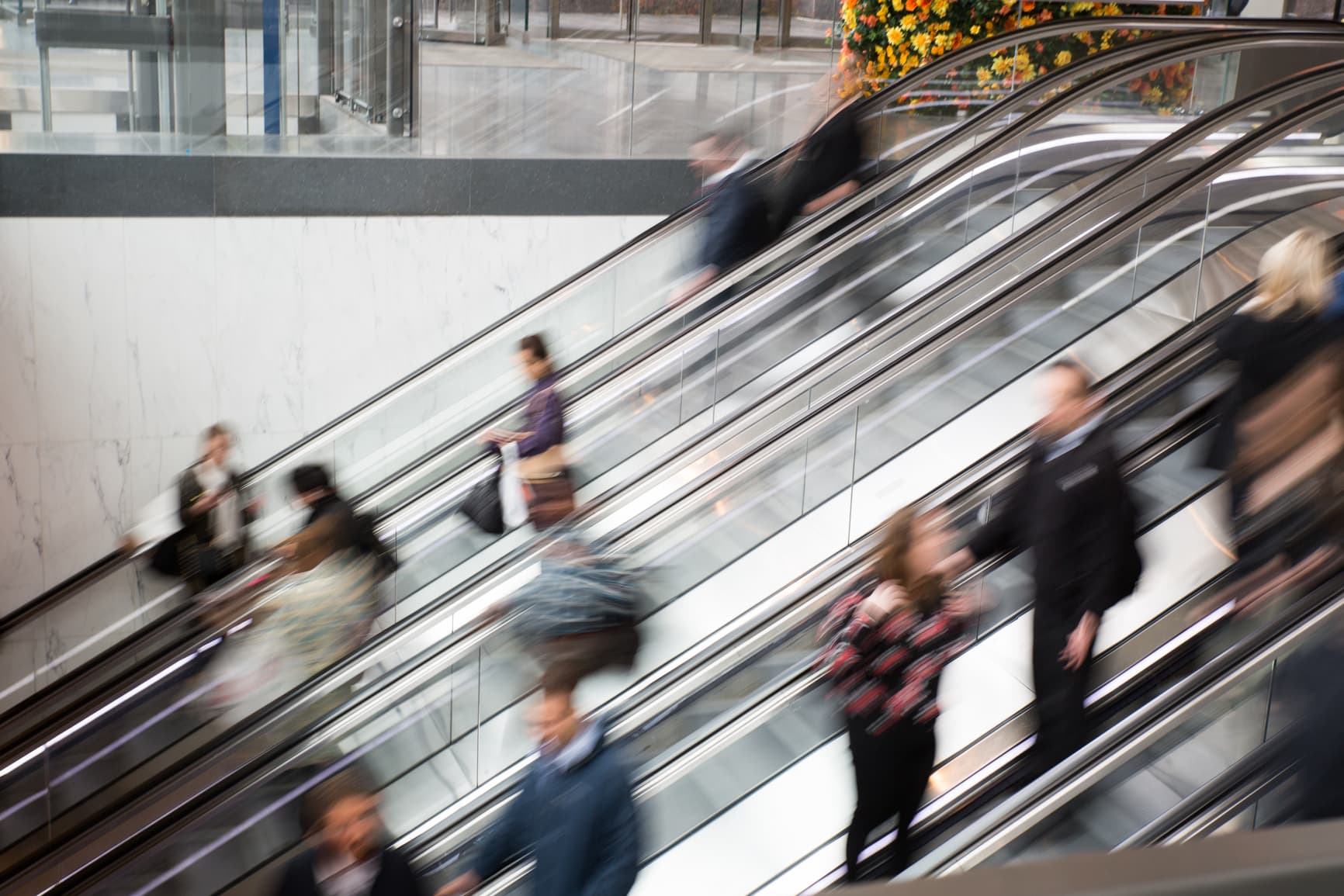 Blurred image of a bunch of people on a escalator in motion.