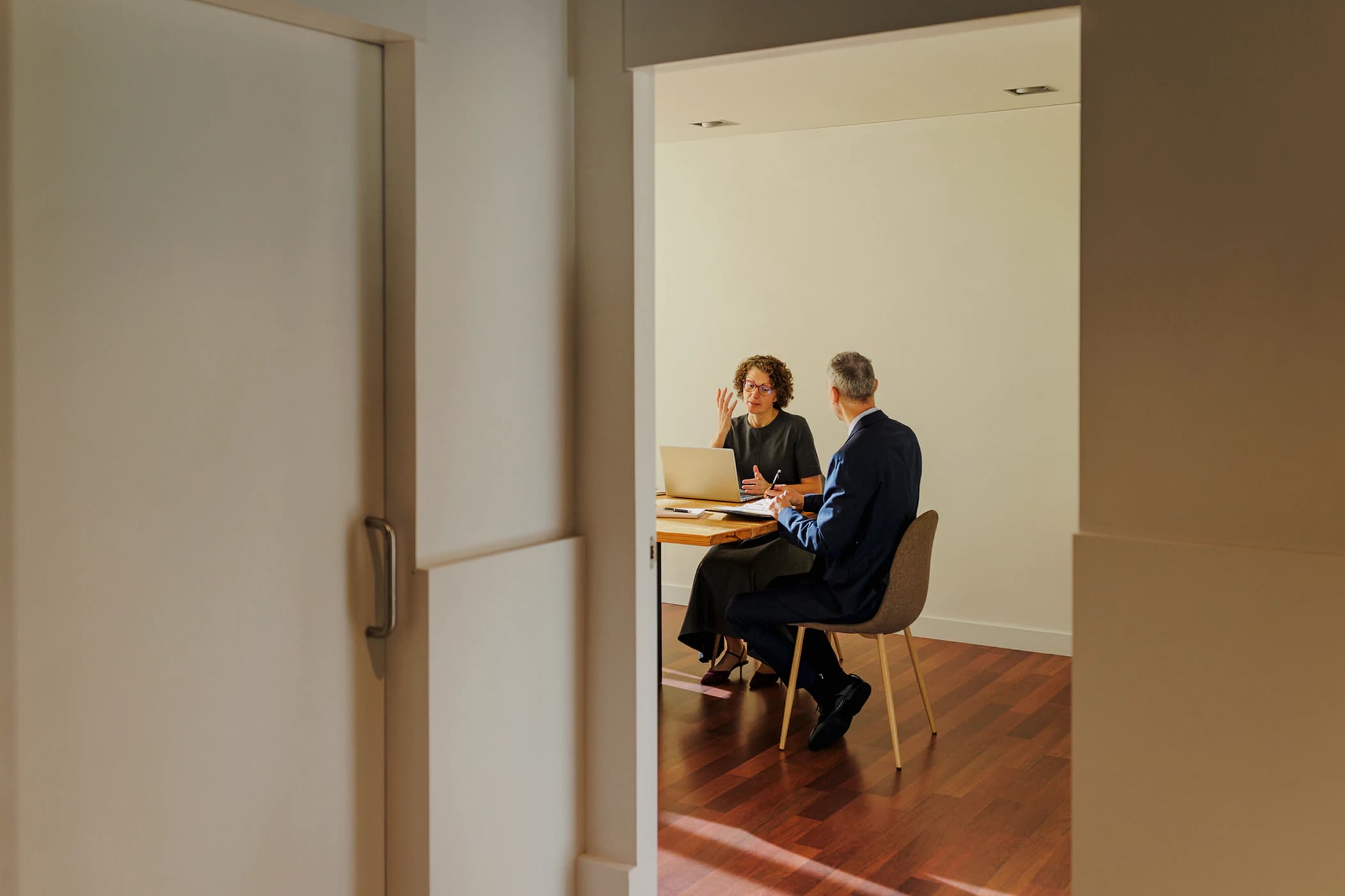 Outside view of a doorway into a meeting room where two individuals are having a meeting.