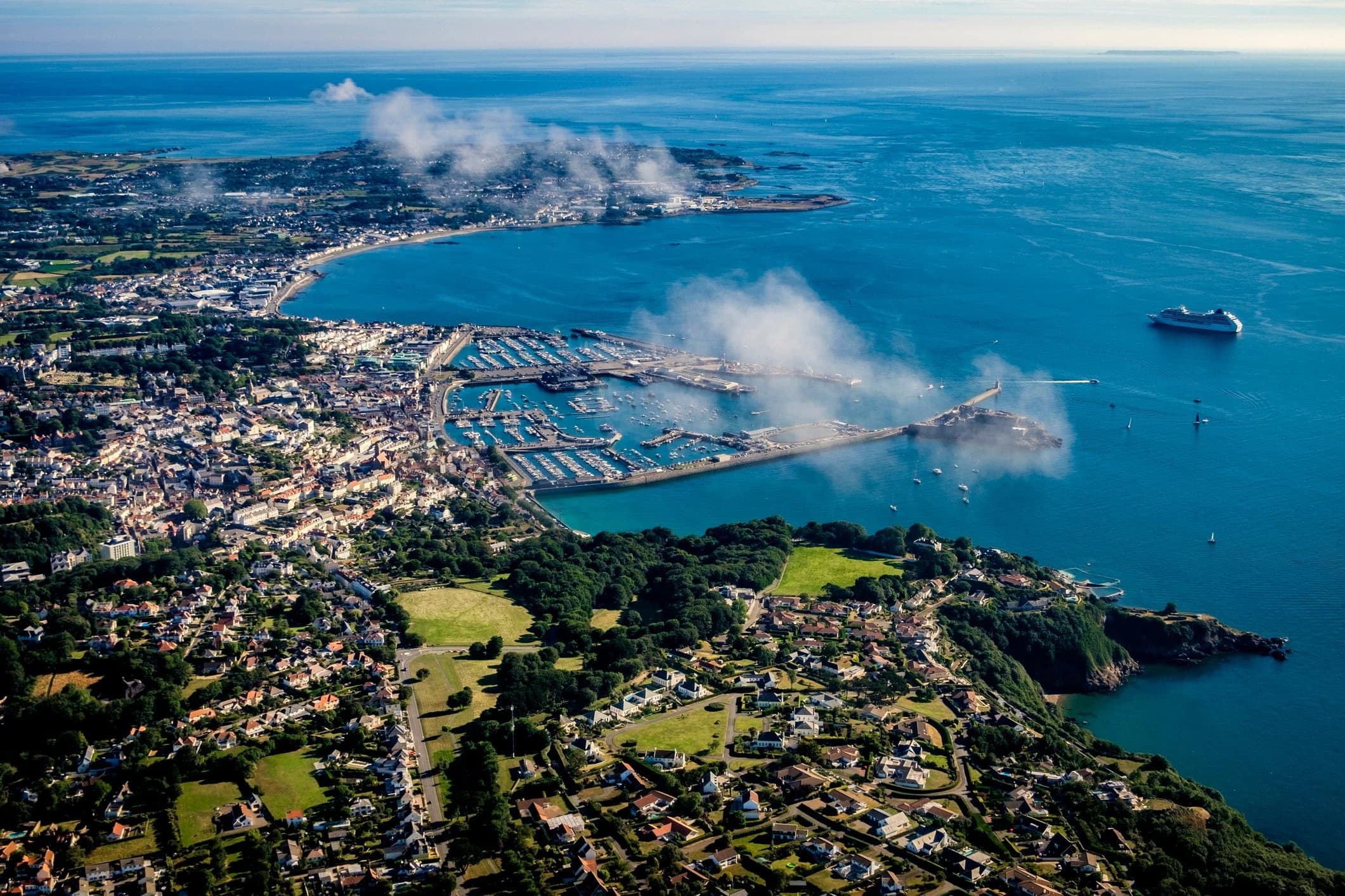 Aerial view of St Peter Port harbour and coastline in Guernsey, with boats moored in the marina and a ferry approaching